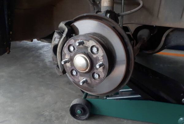 A car on jack with wheel removed showing brake discs