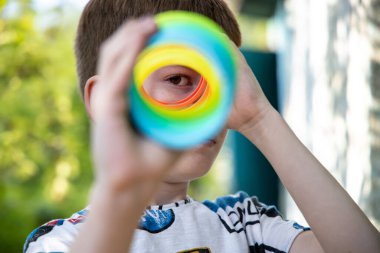 Genç çocuk teleskop gibi renkli oyuncaklardan bakıyor..