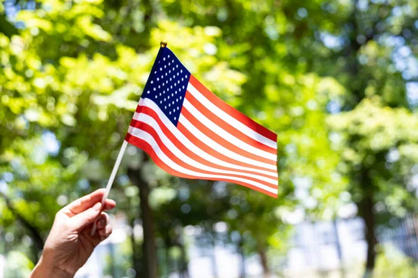 アメリカ独立記念日 緑の木の背景に女性の手にアメリカ国旗 7月4日 — ストック写真