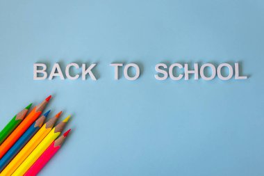 Okul konseptine geri dönelim. Açık mavi arka planda renkli neon kalemler. Boşluğu kopyala, ders için yer aç. Okul malzemeleri..