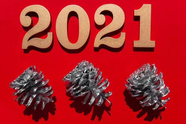 New year red background with shiny golden numbers 2021 and silver pine cone. Minimalistic concept at red paper with hard shadows. — Stock Photo, Image