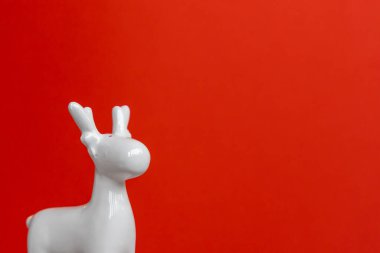 Noel afişi. Kırmızı arka planda beyaz geyik. Uzayı kopyala Tebrik kartı