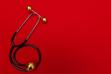 Kırmızı arka planda steteskoplu tıbbi Noel afişi. 