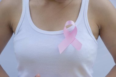 Göğsünde pembe kurdele kullanan bir kadın.