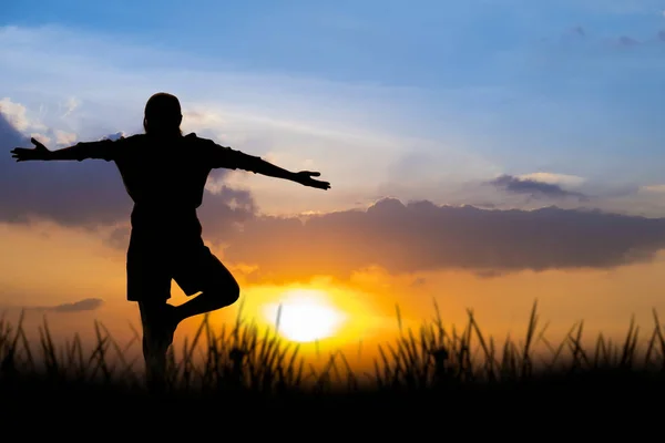 Silhouette asiatisch frau yoga bei sonnenuntergang. — Stockfoto