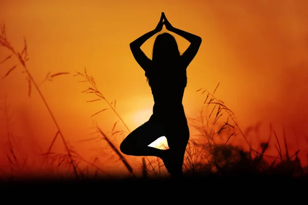 Silhouette asiatisch frau yoga bei sonnenuntergang. — Stockfoto