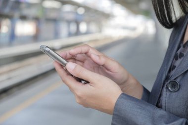 Tren istasyonunda akıllı telefon kullanan bir iş kadını..