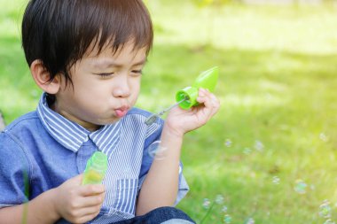 Cute Asian child playing with bubbles in the park