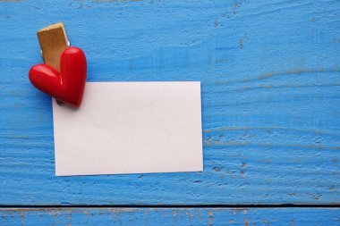 ahşap arka plan üzerinde kırmızı kalp sembolü ve kağıt not