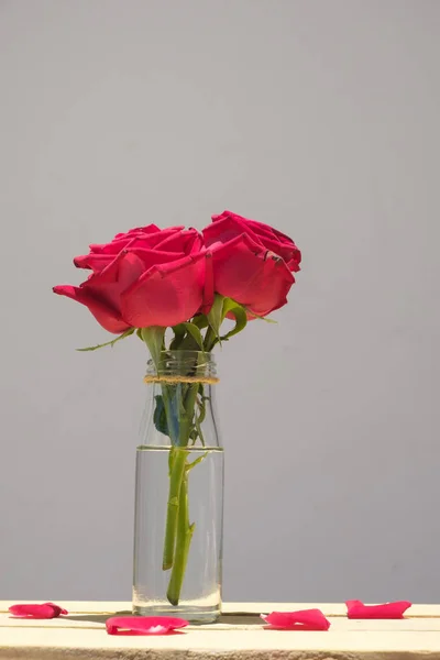 Still life with red rose on wooden table