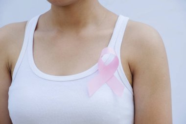 Göğsünde pembe kurdele kullanan bir kadın.