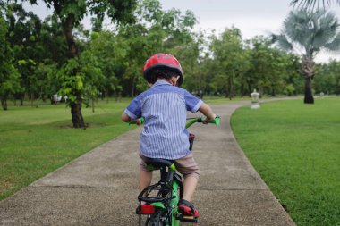 Genç Asyalı çocuk parkta bisiklete biniyor