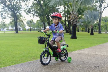 Genç Asyalı çocuk parkta bisiklete biniyor