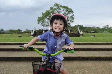 Genç Asyalı çocuk parkta bisiklete biniyor