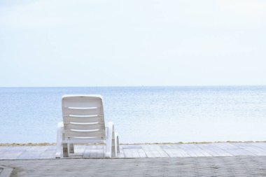 Sahilde beyaz plastik sandalye.