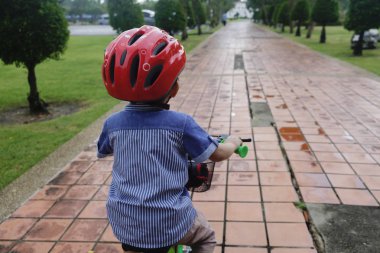 Genç Asyalı çocuk parkta bisiklete biniyor