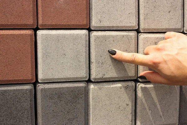 A woman points at a paving stone at an exhibition stand