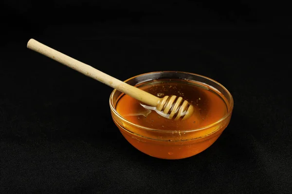 黒を基調とした木の棒を持つボウルに蜂蜜 — ストック写真