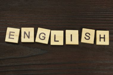 Koyu ahşap bir arka planda İngilizce kare harfler.