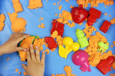 Kinetik kum. Çeşitli şekillerde kumdan kale inşa eden çocuk