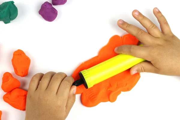 A child plays with colored modeling clay, plasticine on a white background
