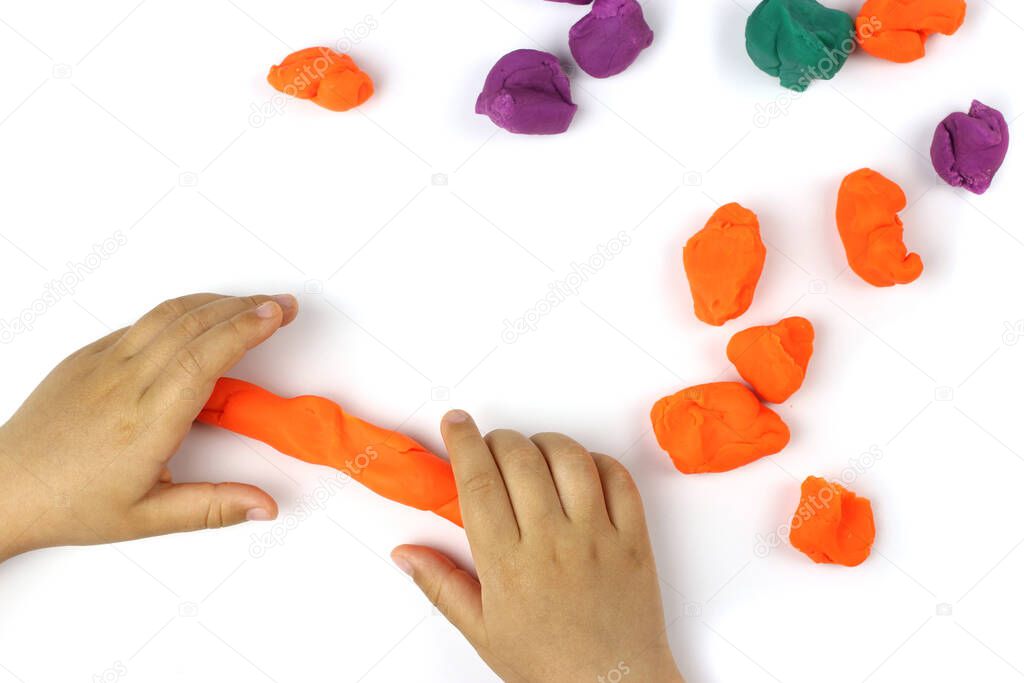 A child plays with colored modeling clay, plasticine on a white background