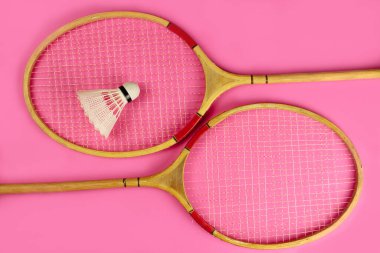Pembe arka planda Shuttlecock ve badminton raketleri