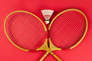 badminton raketleri ve parlak kırmızı arka planda bir mekik.