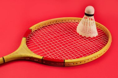 Shuttlecock, parlak kırmızı arka planda badminton raketinde