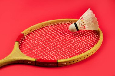 Shuttlecock, parlak kırmızı arka planda badminton raketinde
