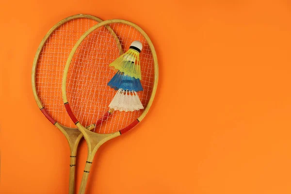 羽毛球球拍和羽毛球在明亮的橙色背景 复制您的文本空间 — 图库照片