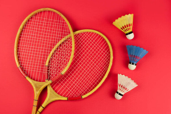 badminton rackets and shuttlecock on a bright red background