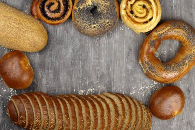 Fırın somunları, rulo ekmekler, gri arka planda simitler. Metin için alanı kopyala
