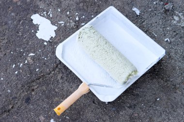 Asfalt zemin üzerinde beyaz boya ile boya silindiri ve tepsisi