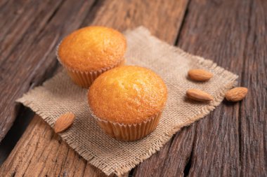 Tahta masadaki çuval kumaşa karşı bir fincan badem keki kapayın ve yüzeysel alan derinliğini seçin.