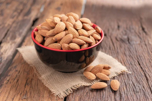 Ahşap masa, select odak alan sığ derinliği karşı seramik bir kasede badem fındık