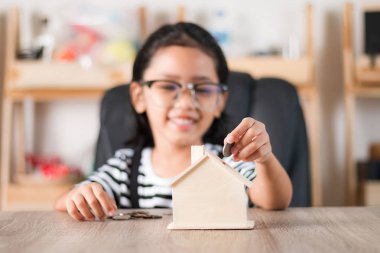 Para içinde ev kumbara sığ derinliği alan seçin odak için evde koyarak Asyalı küçük kız