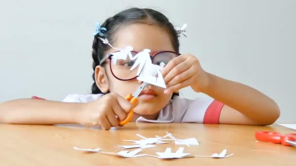 亚洲小女孩在泰国幼稚园学生制服使用剪剪的白色纸做家庭形状父亲母亲儿子和女儿在木桌选择焦点在手 — 图库视频影像