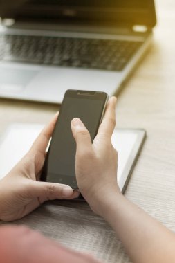Ahşap masa üzerinde akıllı telefon kullanan kadın elinde