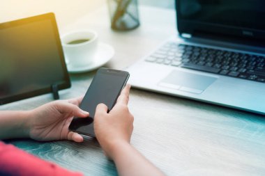 Ahşap masa üzerinde akıllı telefon kullanan kadın elinde