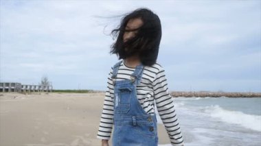 Yavaş hareket Asyalı küçük gülümseme ve sahilde gülüyor