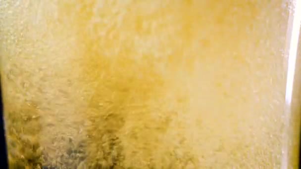 Bière 4K à mouvement lent versant dans le verre avec bulle sur fond sombre 