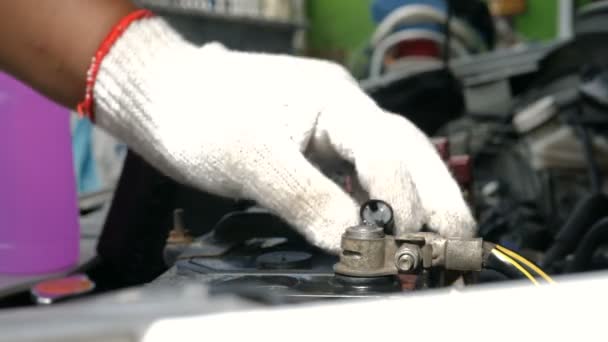 クローズ アップ ショットのメカニックの手を緩めて注いで蒸留水補充電源保守用車バッテリー供給のキャップを締める — ストック動画