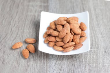 Ahşap masa, select odak alan sığ derinliği karşı seramik bir kasede badem fındık