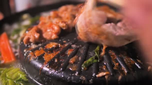 調理のピックは 箸を使用してと豚肉を反転し 暗いと鍋と穀物の処理で焼肉バーベキュー会 — ストック動画