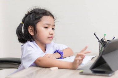 Asyalı küçük kız öğrenci üzerinde ahşap ta ödev üniforma