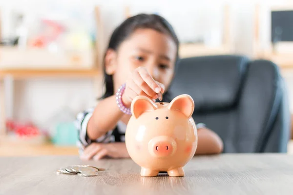 Asiática niña en poner moneda en a alcancía superficial profundidad —  Fotos de Stock