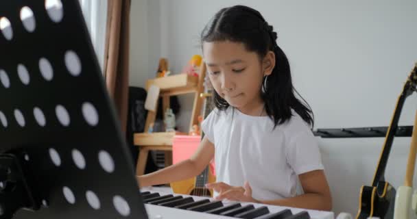 가정에서 공부하는 신디사이저 키보드를 사용하여 피아노를 연주하는 배우는 아시아 — 비디오