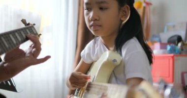 Asyalı küçük kız evde eğitim acemi müzik enstrümantal kendini için elektrik gitar kullanarak temel gitar çalmayı öğrenme