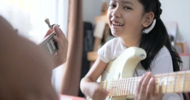 Asyalı küçük kız evde eğitim acemi müzik enstrümantal kendini için elektrik gitar kullanarak temel gitar çalmayı öğrenme